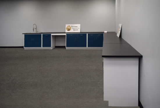 Blue laboratory cabinets with black countertops and two desks.