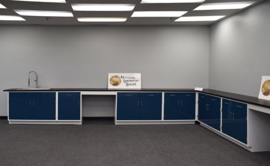 Blue laboratory cabinets with black countertops and two desks.