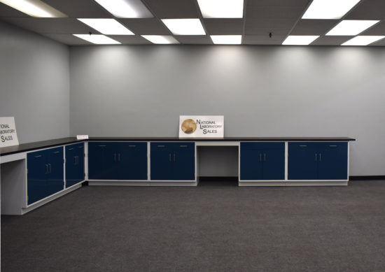 Blue laboratory cabinets with black countertops and two desks.